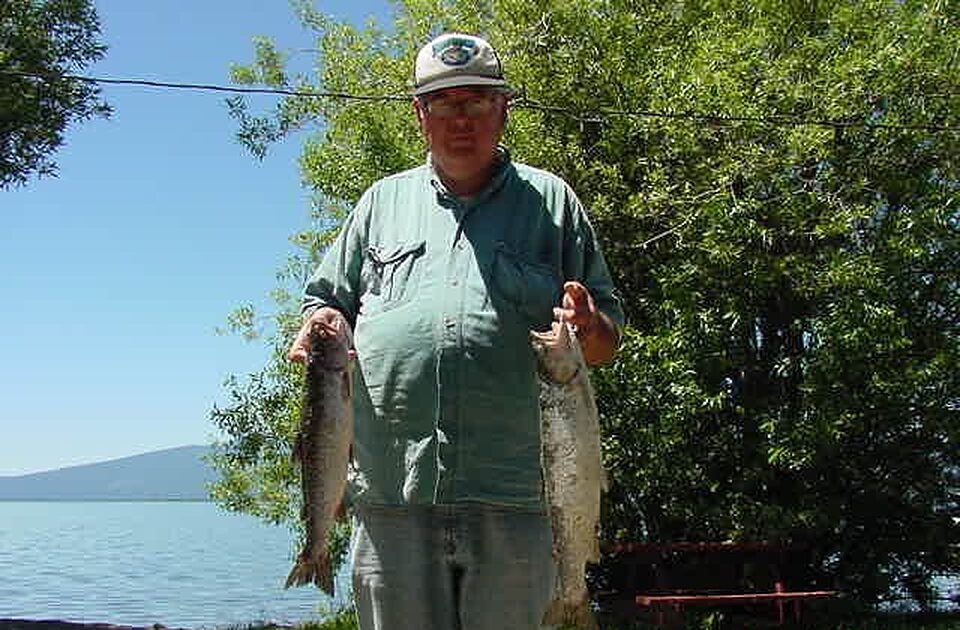 Angler holding two trout on the lakeshore