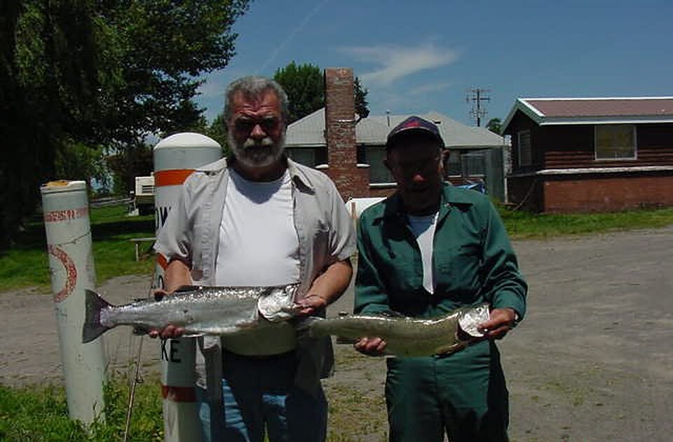 Two anglers showing their trout by the cabins