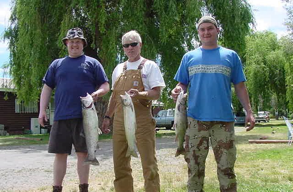 Three anglers with their catch on the lawn
