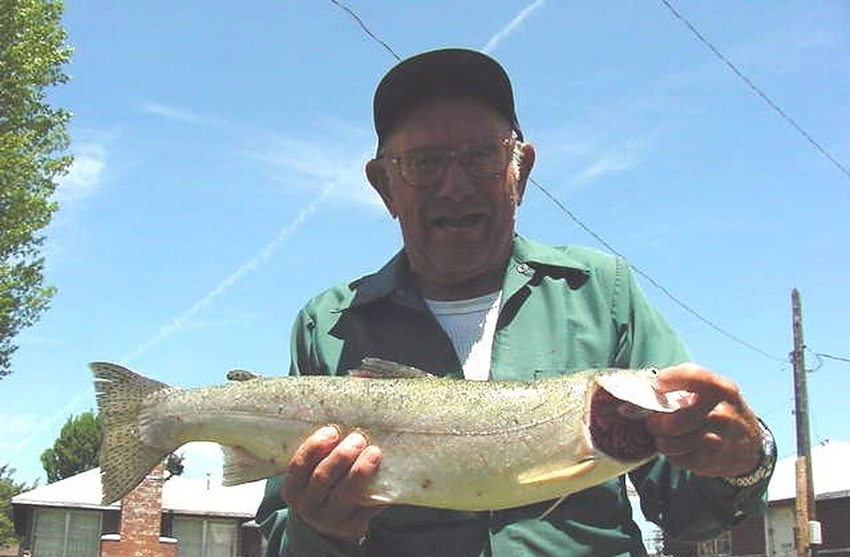 Angler in a cap holding up a trout
